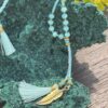 This is turquoise blue crystal beads necklace featuring Ohm and feather accents