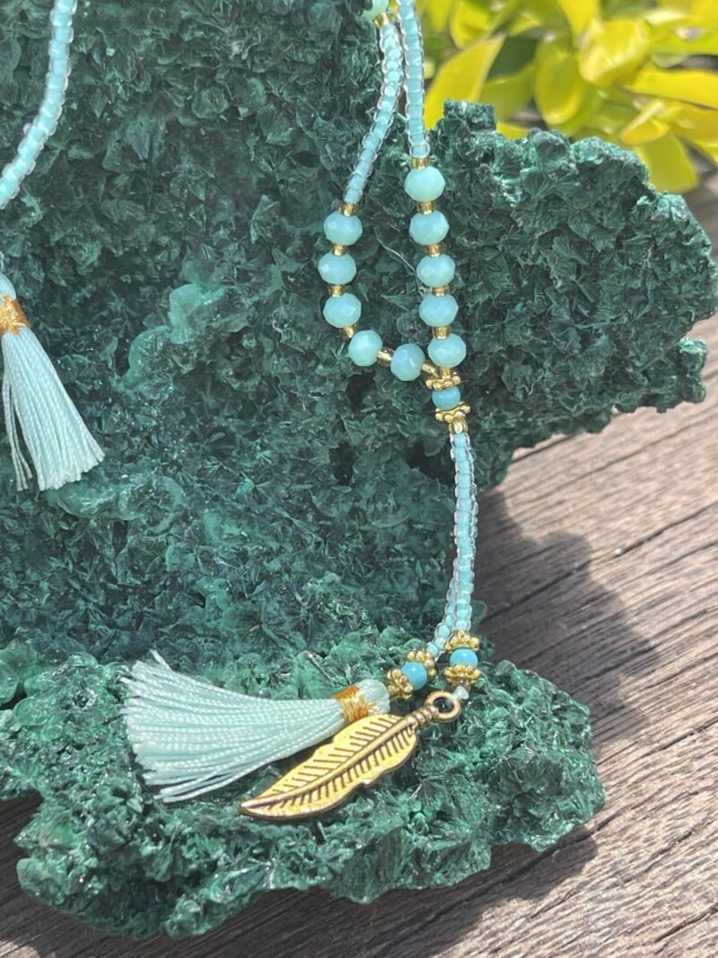 This is turquoise blue crystal beads necklace featuring Ohm and feather accents